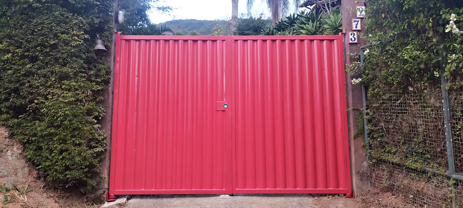 Portão pivotante com duas folhas em ferro batido e chapa búzios na cor vermelha