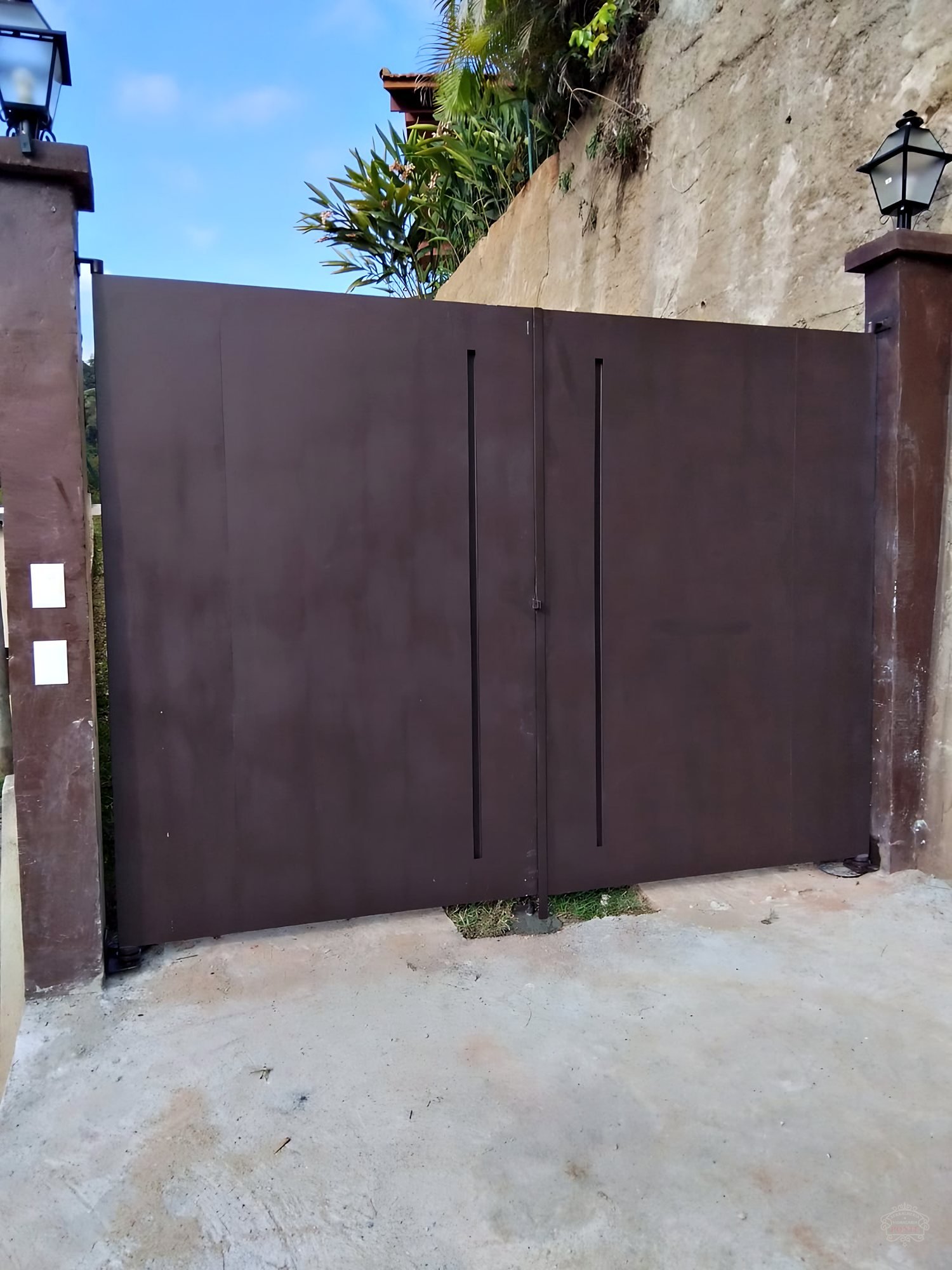 Portão pivotante em ferro chapeado, com detalhe do puxador embutido